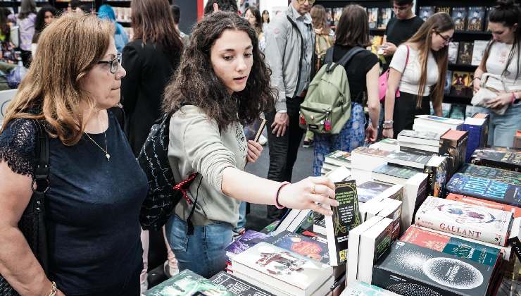 Una signora e una ragazza che sfogliano libri al Salone del libro di Torino