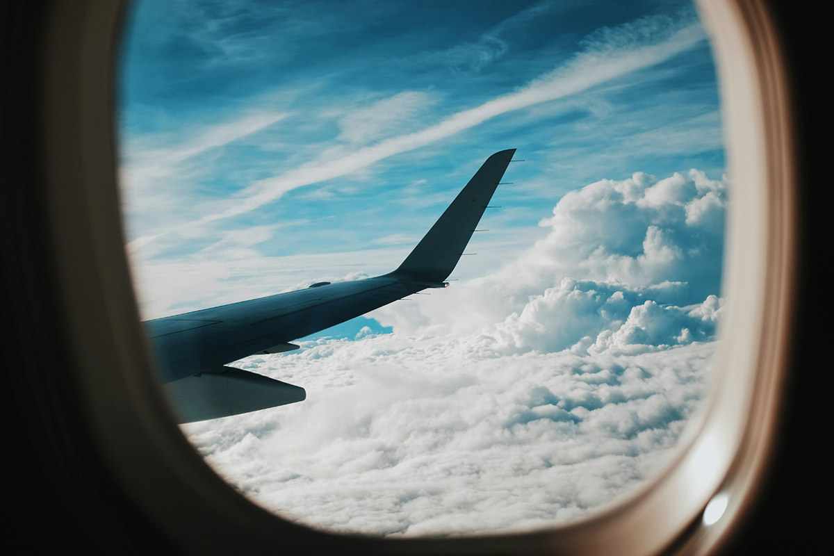 Eventi nel mondo, viaggiare in aereo permette di non perderseli. Nell'immagine: la vista fuori dal finestrino di un aereo, con un pezzo del velivolo e delle nubi