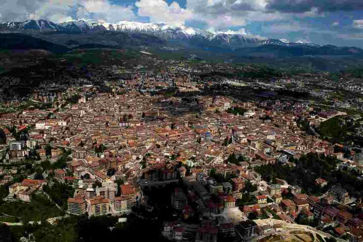 una veduta dell'Aquila dall'alto con il Gran Sasso sullo sfondo