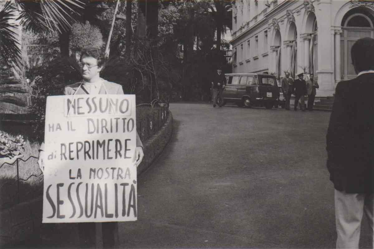 foto in bianco e nero di Angelo Pezzana con un cartello in mano che manifesta il 5 aprile 1972