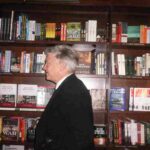 foto di profilo di David Lynch e sullo sfondo una libreria di legno con molti libri
