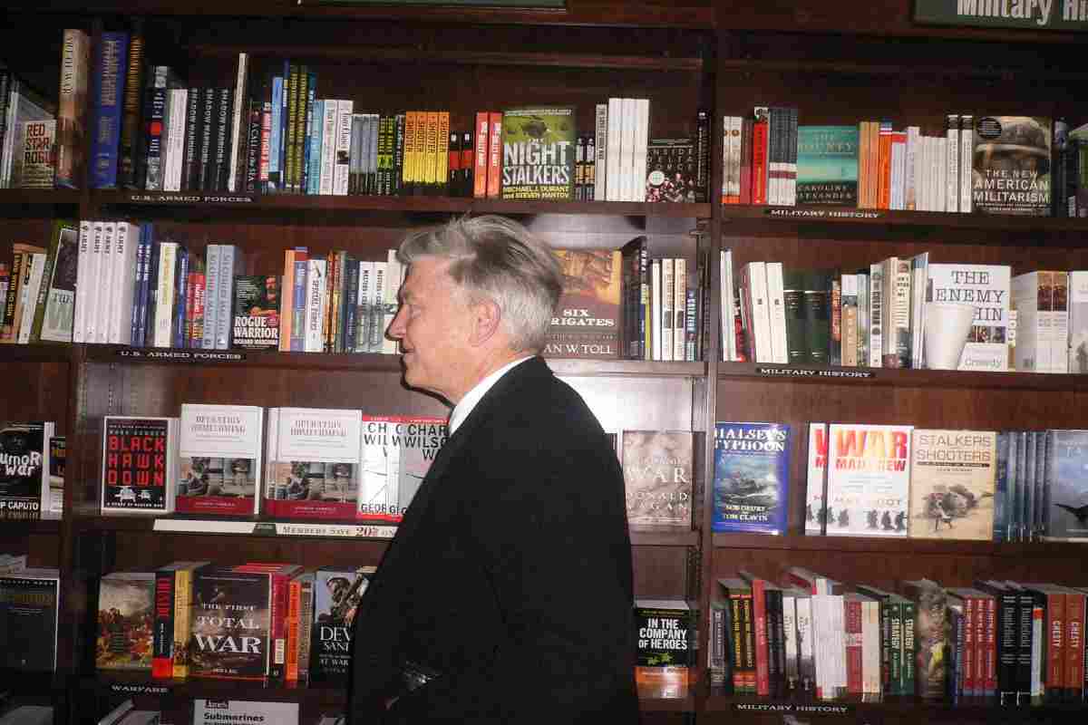 foto di profilo di David Lynch e sullo sfondo una libreria di legno con molti libri