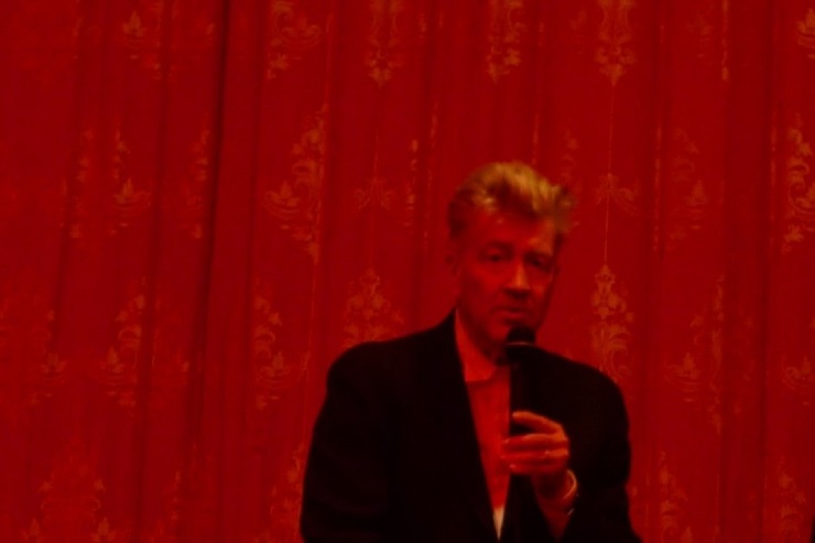 foto di David Lynch con microfono su unta tenda di broccato rosso