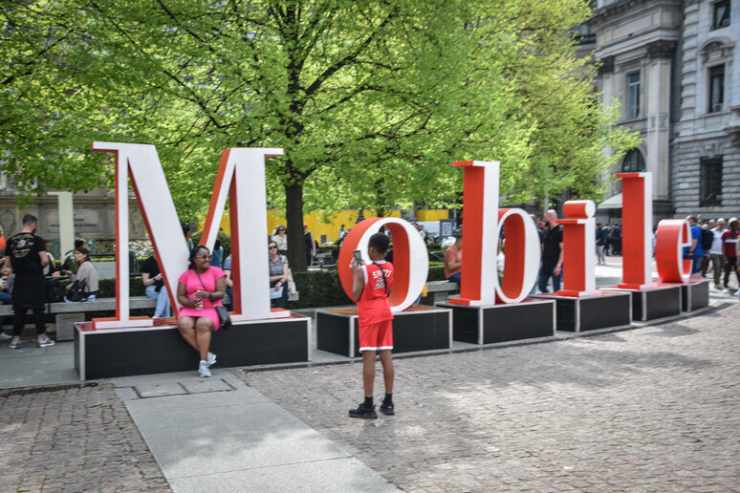 foto dell'esterno della fiera con una grande scritta "Mobile" in bianco e rosso con due persone davanti